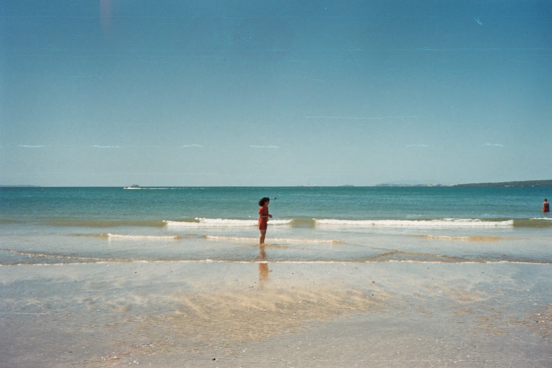 asian women standing in the sand with ocean in background
